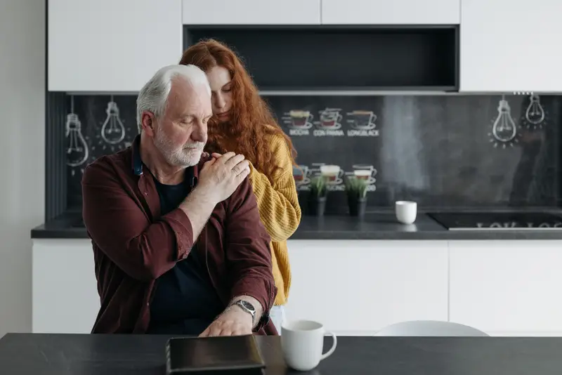 A daughter comforts her father at home